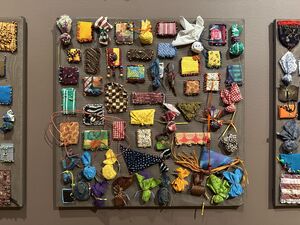 A panel to which is affixed a variety of fabric swatches in various patterns — some beaded, some folded 